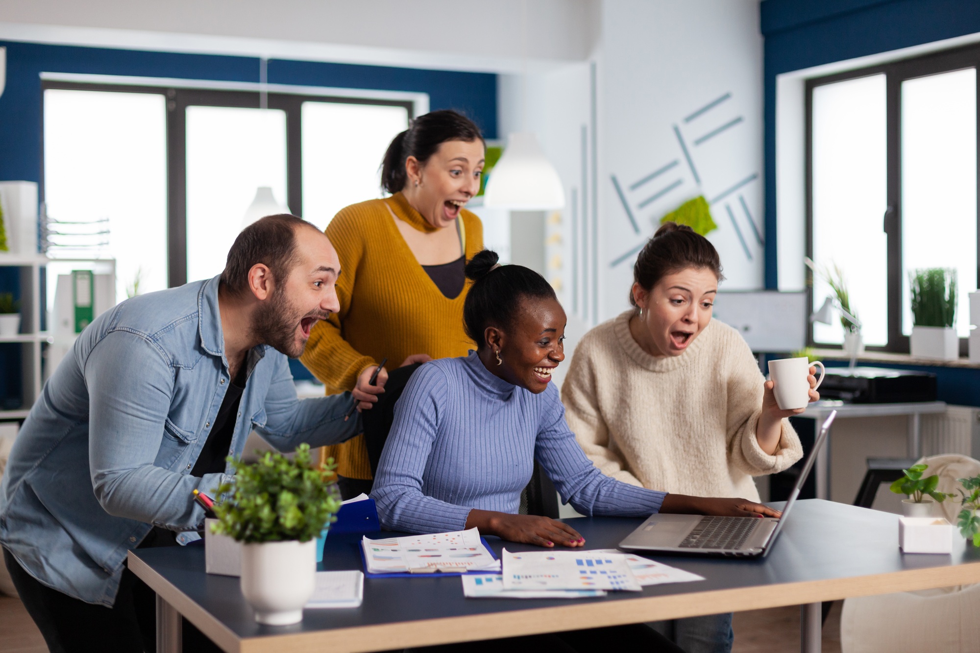 Excited diverse coworkes in statup company office celebrate